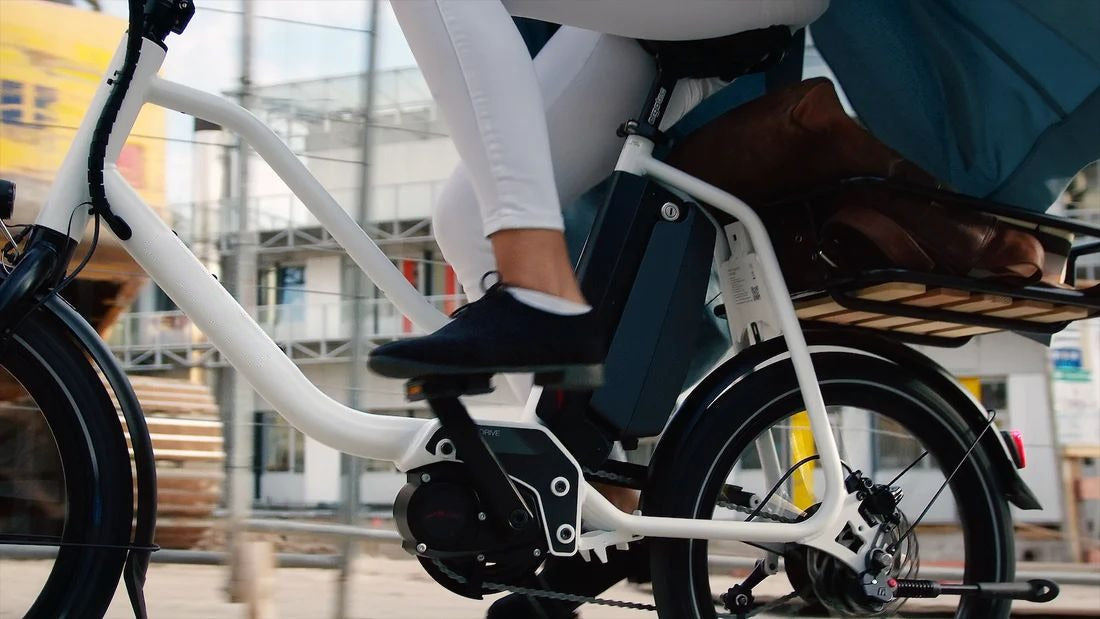 Nanno Bike with cargo rack ridden by a woman in urban setting